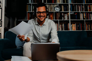© iStock_DuxX Mann mit Notebook und eine Seite Papier.